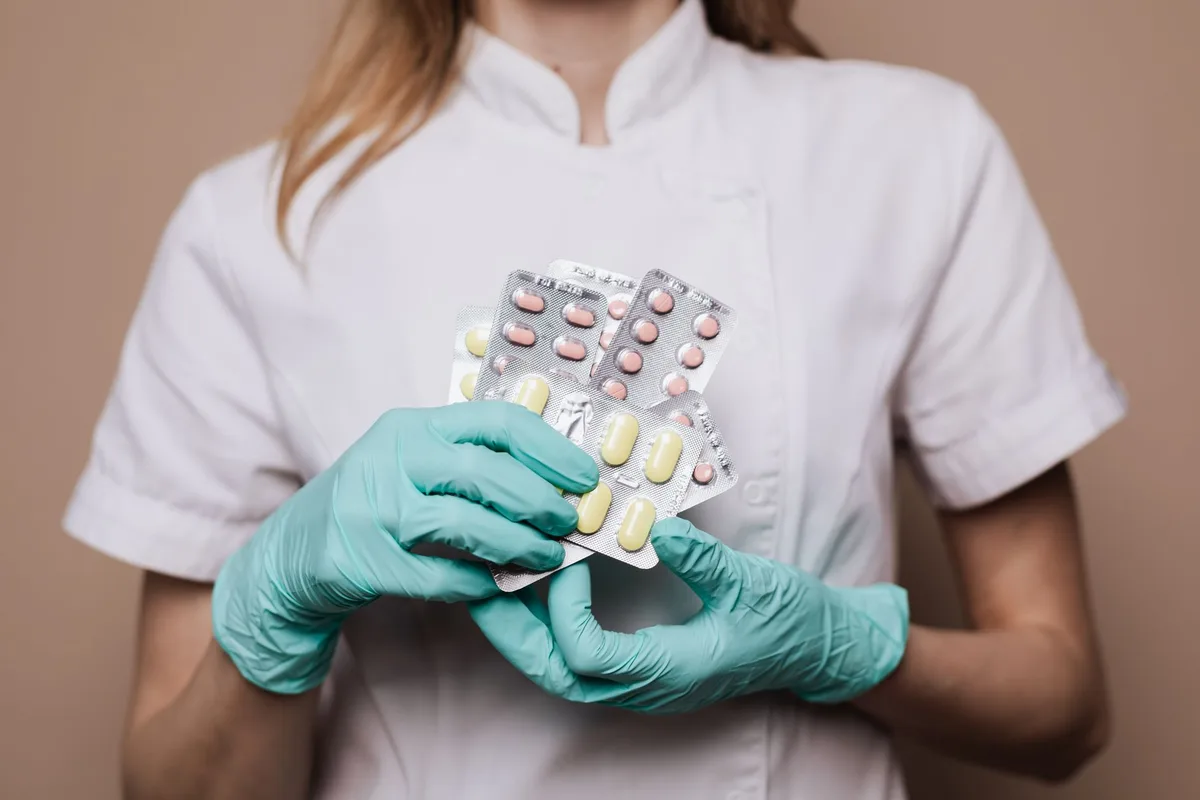 Profesional de salud con guantes sosteniendo blísteres de medicamentos